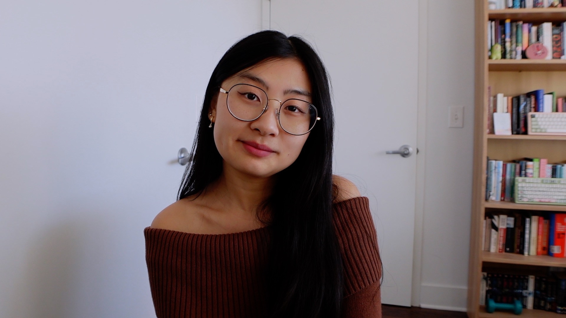 An Asian 31 year old girl smiling in an off-shoulder brown shirt